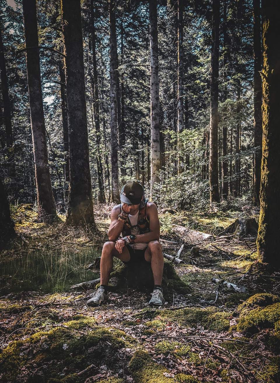 Benjamin Degrève assis sur une souche, en forêt